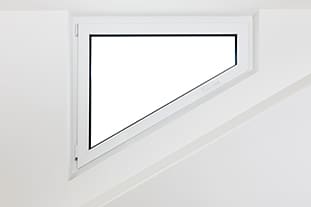 Ein weiß gerahmtes Dreiecksfenster, eingebettet in eine minimalistische weiße Wand, mit offenem Design und Dreh-Kipp-Funktion.
