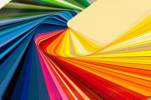 Eine fächerförmig angeordnete Auswahl bunter Farbmuster, die eine breite Palette von Farbtönen von Gelb und Orange bis hin zu Blau, Grün und Rot zeigen und in einem überlappenden Muster angeordnet sind.