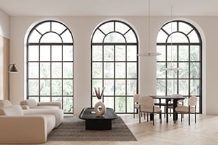 Moderner Raum mit großen Rundbogenfenstern und eleganten Sprossen, neutral Möbeln, einem beigen Sofa, schwarzem Couchtisch und sichtbarem Grün draußen.